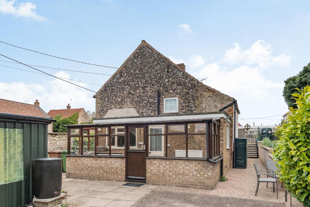 una vista exterior de una casa con un salón acristalado en Violet Cottage en Feltwell