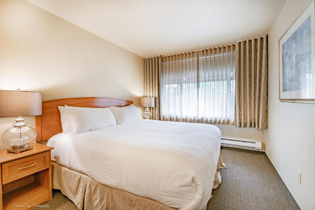 Un dormitorio con una gran cama blanca y una ventana en La Residence Suite Hotel, en Bellevue