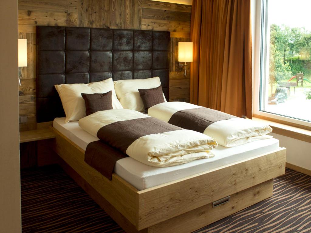 a bedroom with two beds with a large window at Alpenflair Hotel in Buchloe