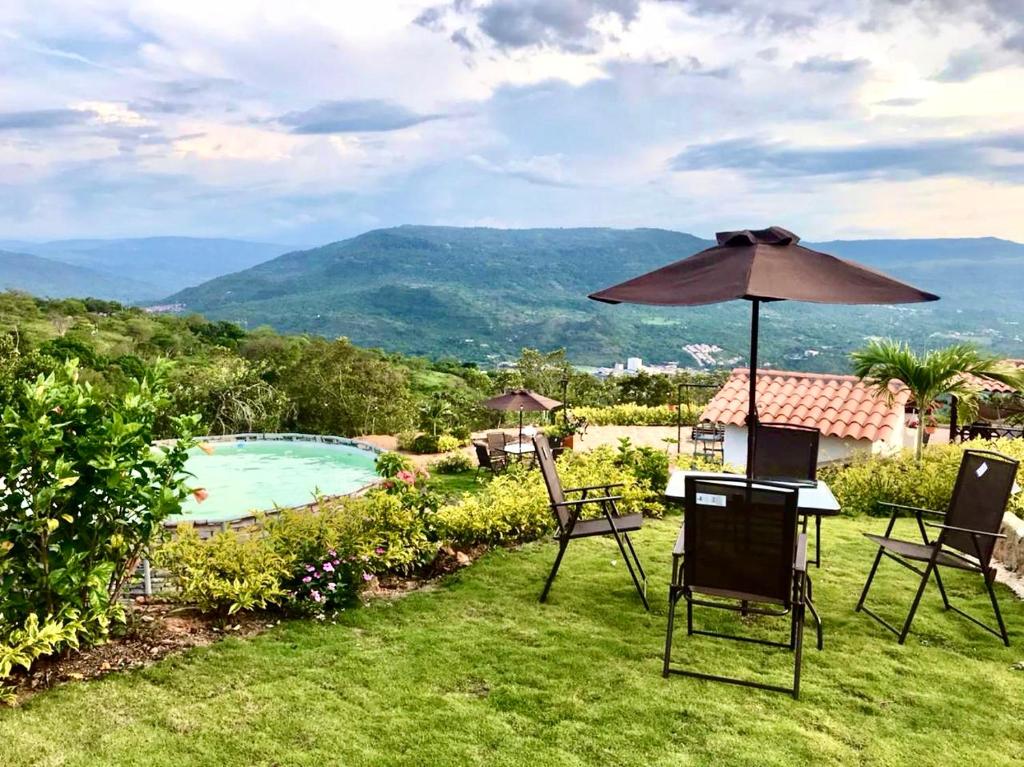 un patio con sombrilla, sillas y piscina en Cabañas San Miguel Arcángel en San Gil