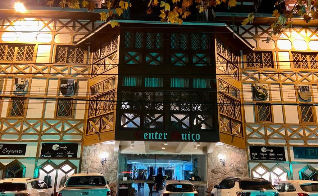 a building with cars parked in front of a store at Flat Centro de Capivari in Campos do Jordão