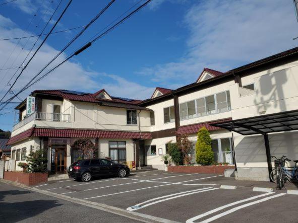 a car parked in a parking lot in front of a building at Ryokan Kume Himawari Sou in Sakaide