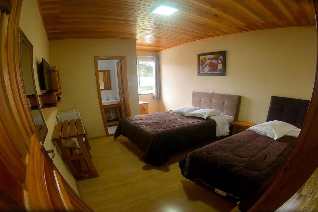 une petite chambre avec deux lits et une télévision dans l'établissement Pousada Gianisella, à Bom Jardim da Serra