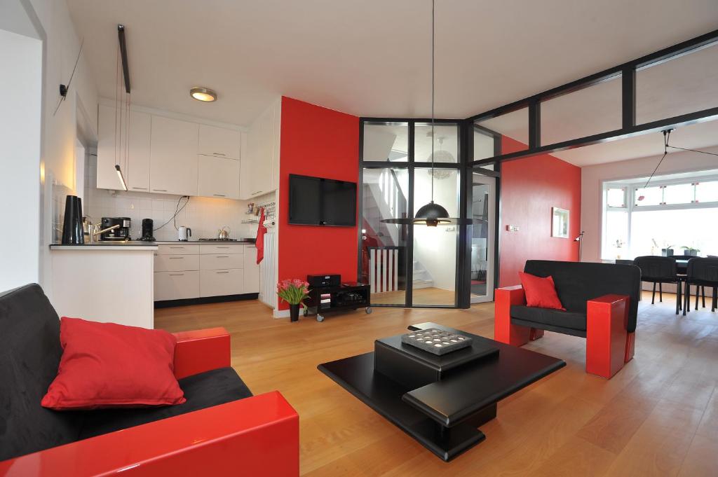 a living room with red and black furniture and a kitchen at Aan't Kanaal in Harlingen