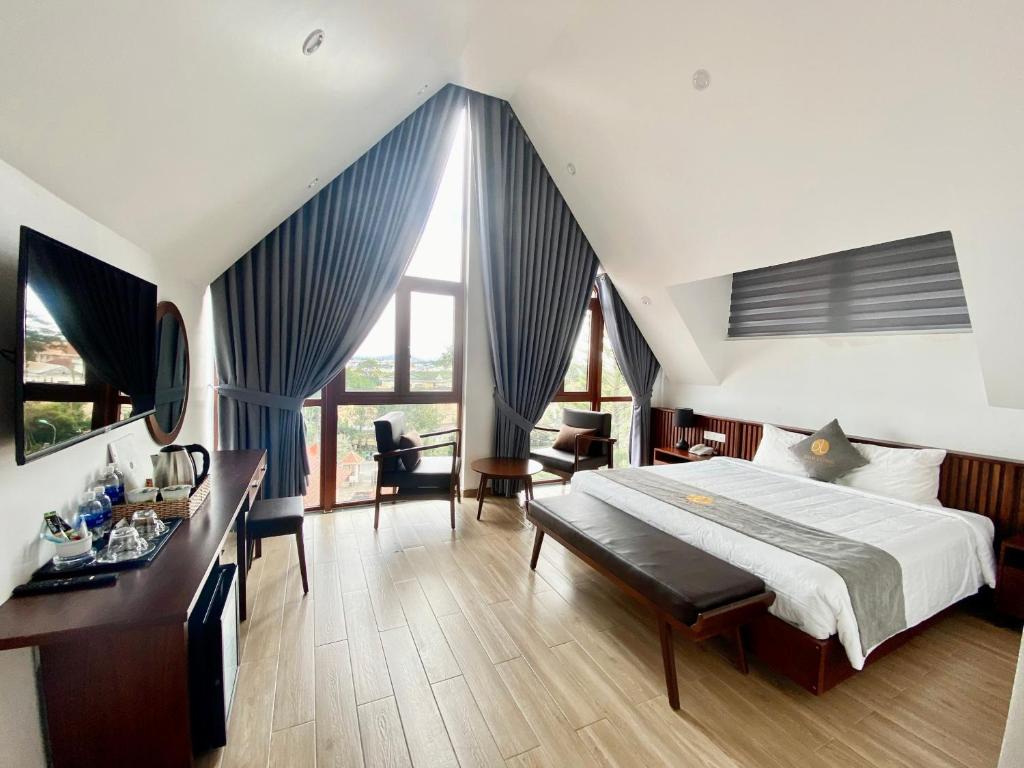 - une chambre avec un grand lit, un bureau et des chaises dans l'établissement Duy Long Hotel, à Đà Lạt
