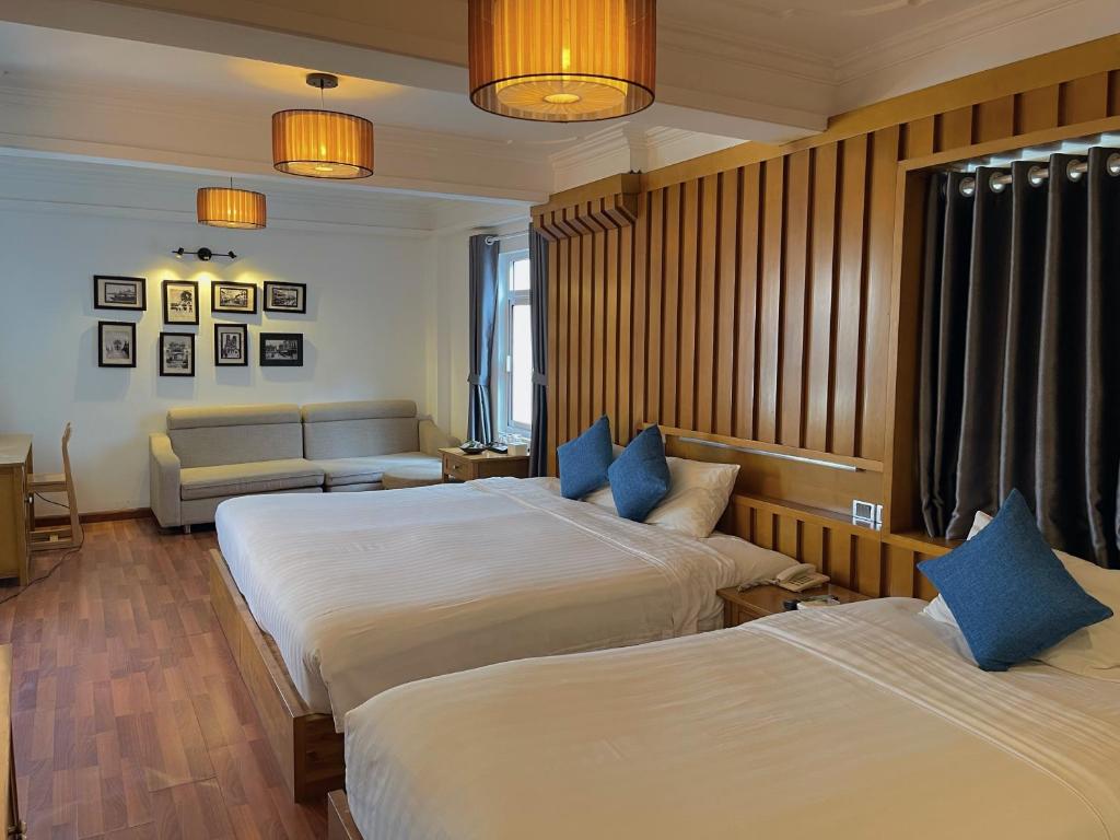 a hotel room with two beds and a couch at Hanoi Central Park Hotel in Hanoi