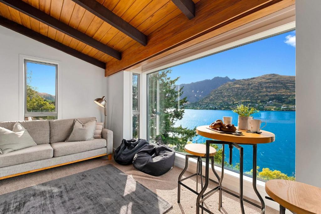 a living room with a couch and a large window at Queenstown Lakefront Dream 4 Bed in Queenstown