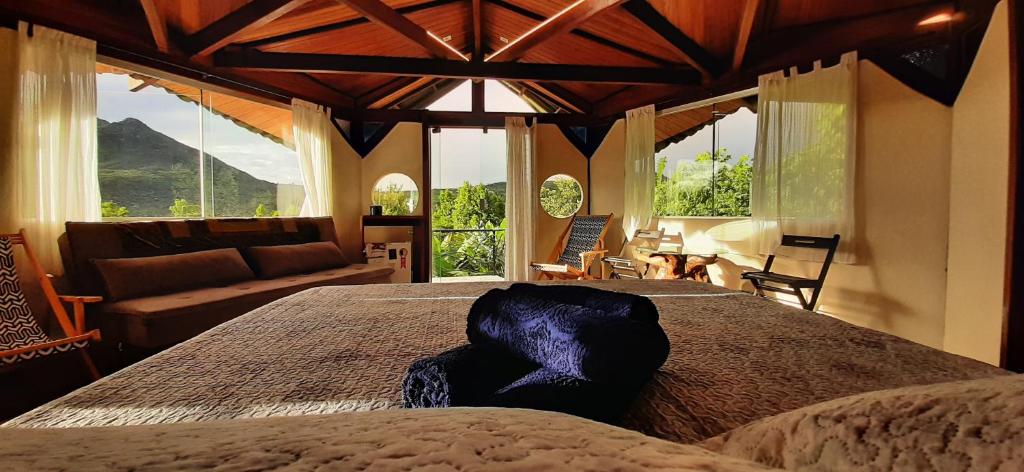 a bedroom with a large bed and a living room at Flor da Vida _ Honeymoon suite - Vale do Capao in Palmeiras