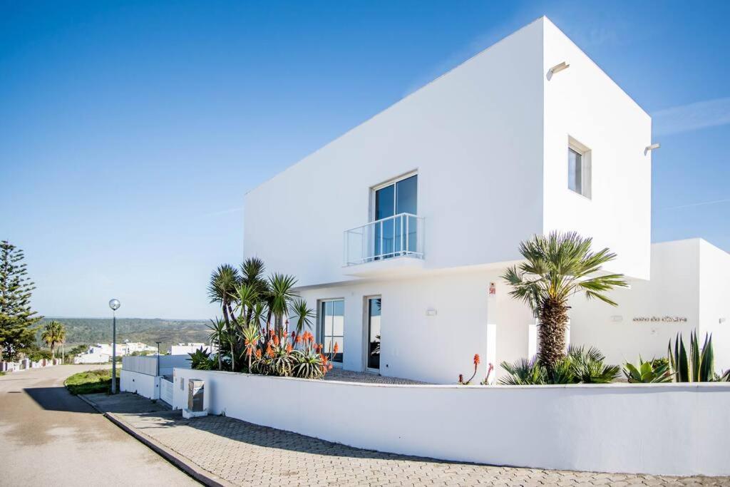 una casa blanca con palmeras delante en Beachside Villa 5 Bdr 6 Baths Sleeps 9plus ppl, en Aljezur