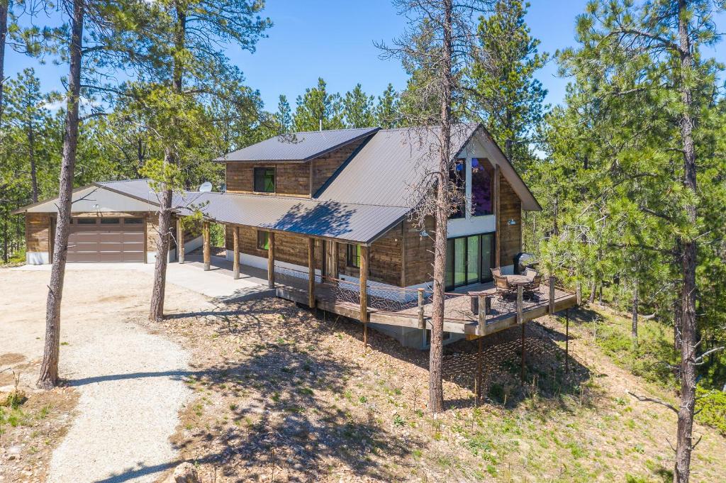 eine Blockhütte im Wald mit einer Veranda in der Unterkunft Gold Nugget Lodge Near Deadwood on 5 Wooded Acres! in Lead