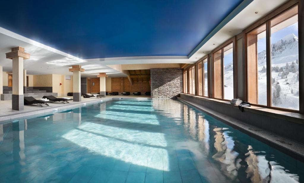 a swimming pool in a hotel with windows at CGH Résidences & Spas Le Village De Lessy in Le Grand-Bornand