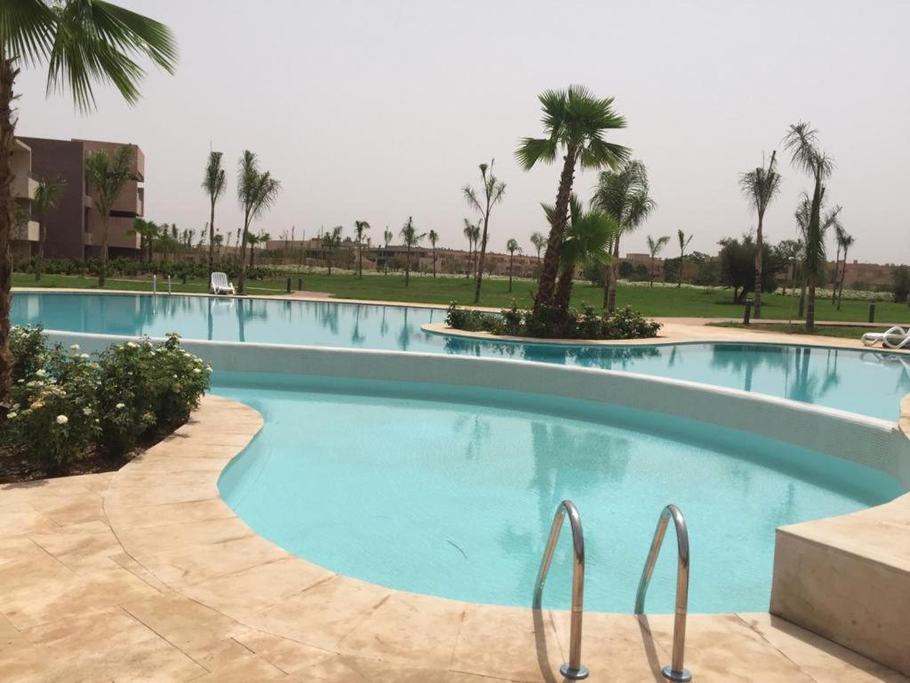 a swimming pool in a resort with palm trees at Appartement résidentiel Prestigia in Marrakesh