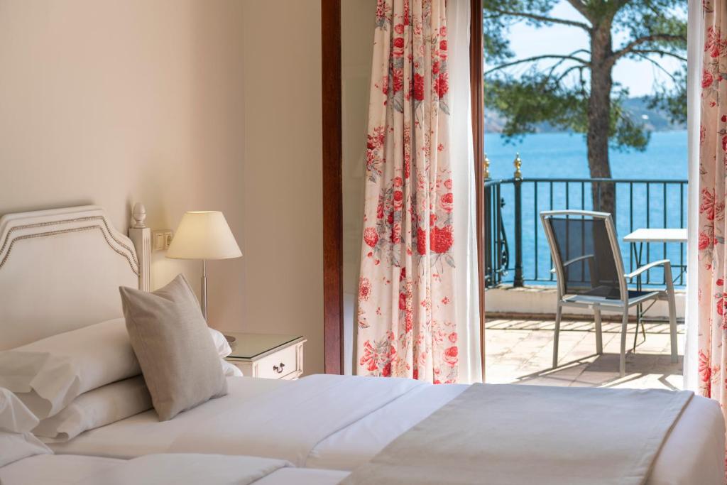 a bedroom with a bed and a balcony with a chair at Hotel Cala Fornells in Paguera