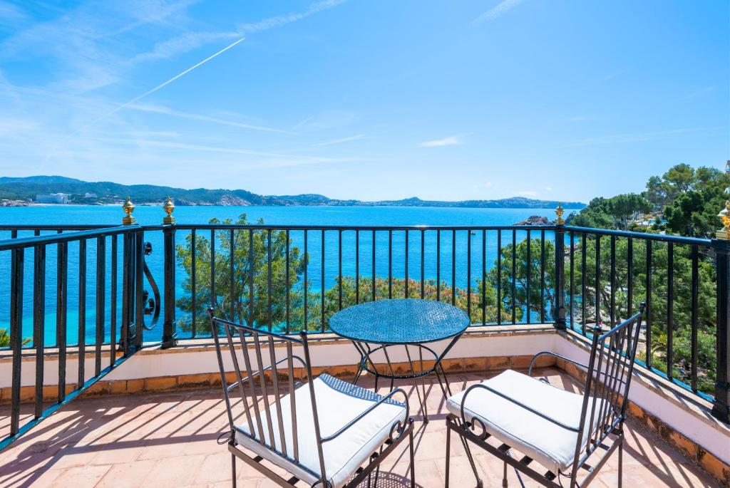 a balcony with a table and chairs and the water at Hotel Cala Fornells in Paguera