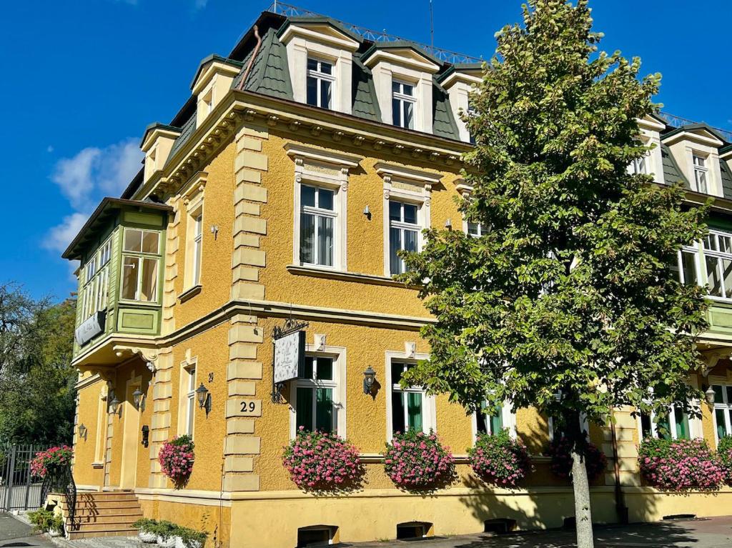 un edificio amarillo con flores delante en Villa Antica, en Kudowa-Zdrój
