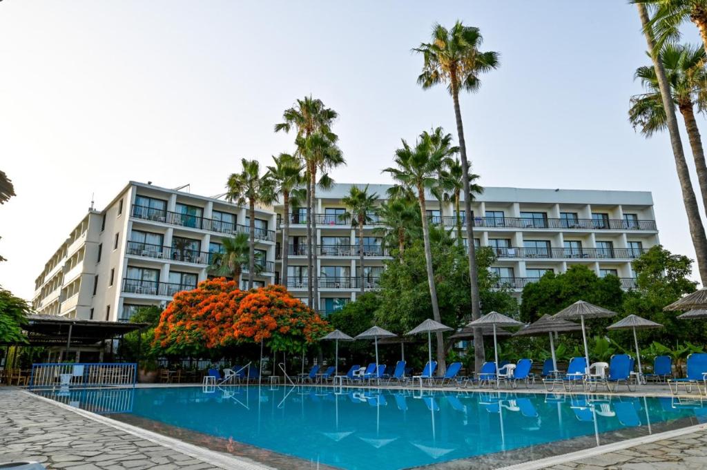 un hotel con piscina, palme e ombrelloni di Veronica Hotel a Paphos