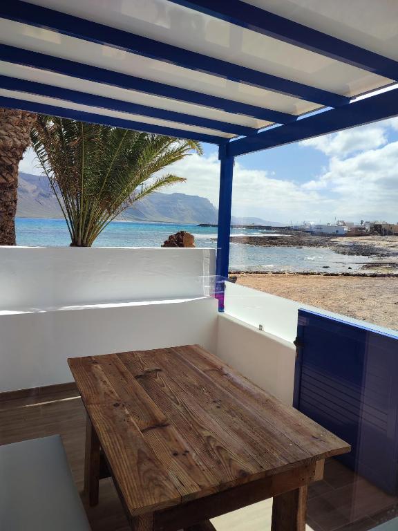 a table on a balcony with a view of the beach at APARTAMENTO LA SAMA in Caleta de Sebo