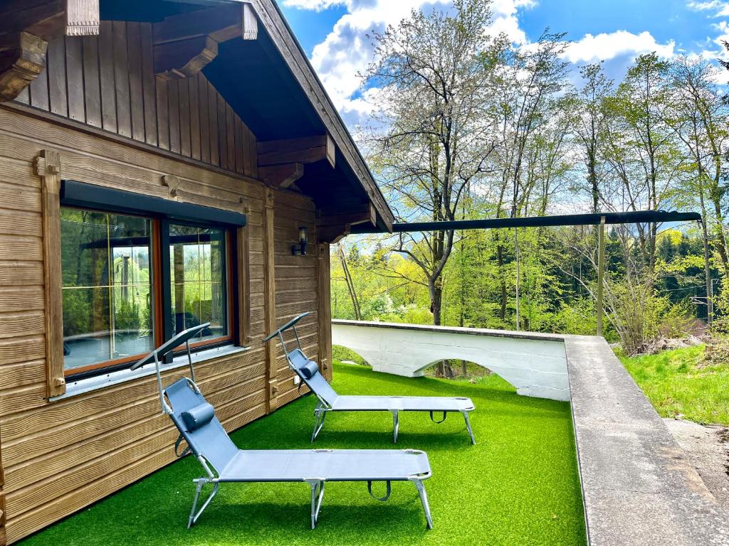 a porch with two chairs and a bench on the grass at Fewo Ziemer 2 in Piding