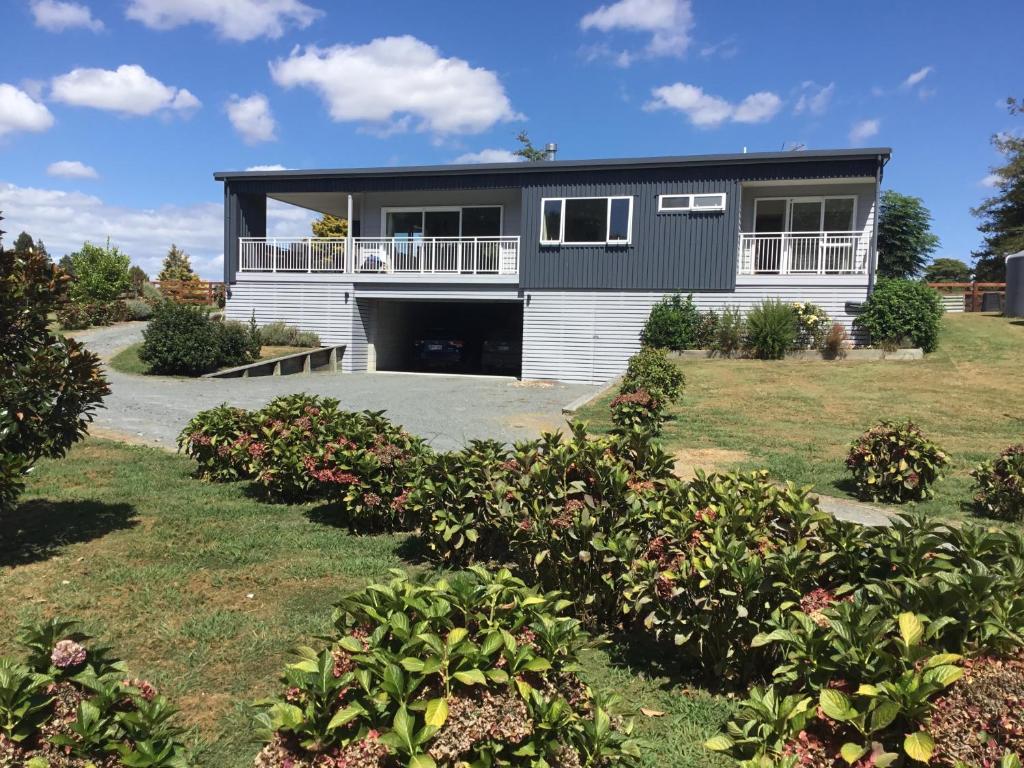 a house with a lot of bushes in front of it at Fairway views B & B in Matamata