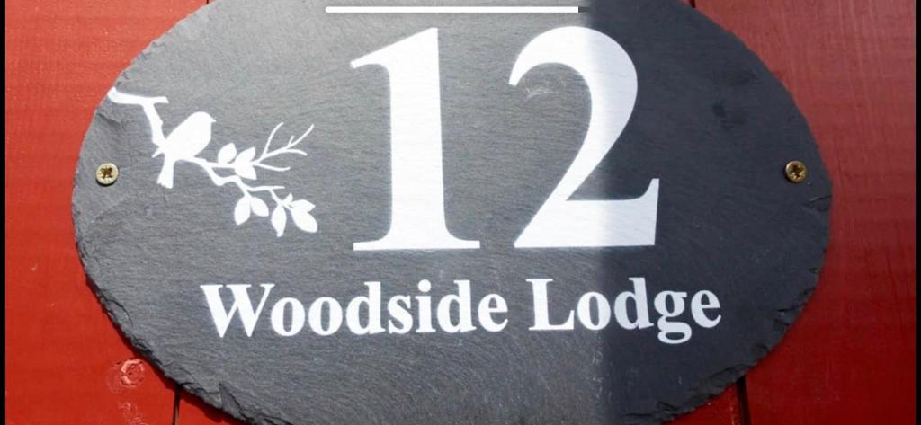 a sign with the number woodisode lodge at Woodside Lodge in Thurstaston