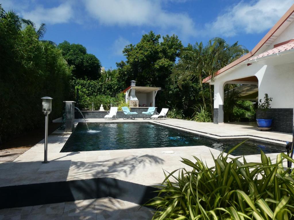 a swimming pool with chairs and a house at KAZE SILAS in Saint-Joseph