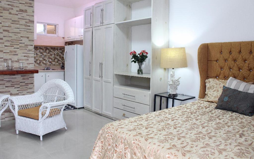 1 dormitorio con 1 cama y 1 silla y cocina en Fully Equipped 1br Studio –dt–2mins To The Beach, en Sosúa