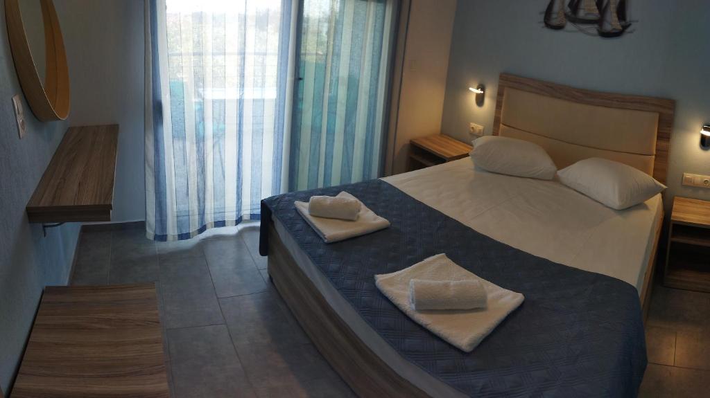 a bedroom with a bed with two towels on it at STUDIOS KOULA 2-DIMOS in Potos