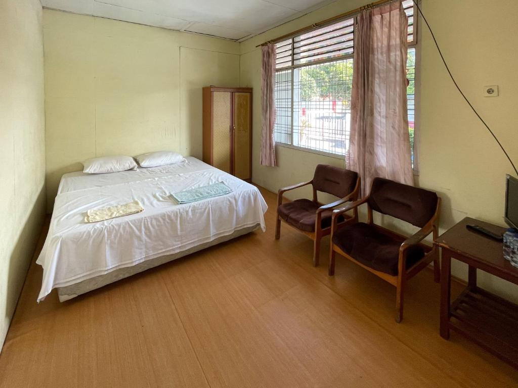 a bedroom with a bed and two chairs and a desk at Valencia Homestay Redpartner in Parapat