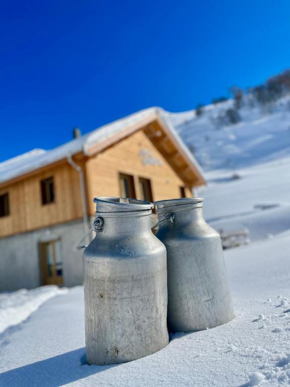 deux vases métalliques assis dans la neige devant une maison dans l'établissement La Ferme des Étroits, à Valloire