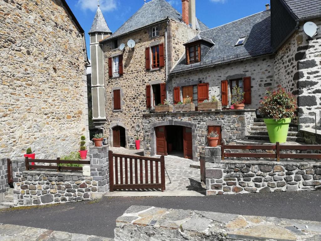 un antiguo edificio de piedra con una puerta y una valla en Maison typique pleine de charme Peyrusse Cantal, en Peyrusse