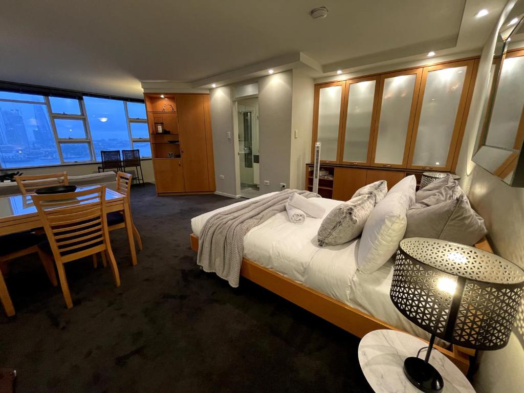 a bedroom with a large bed and a dining room at KOZYGURU McMahons Point Amazing Water View Studio + FREE Parking NMP002 in Sydney