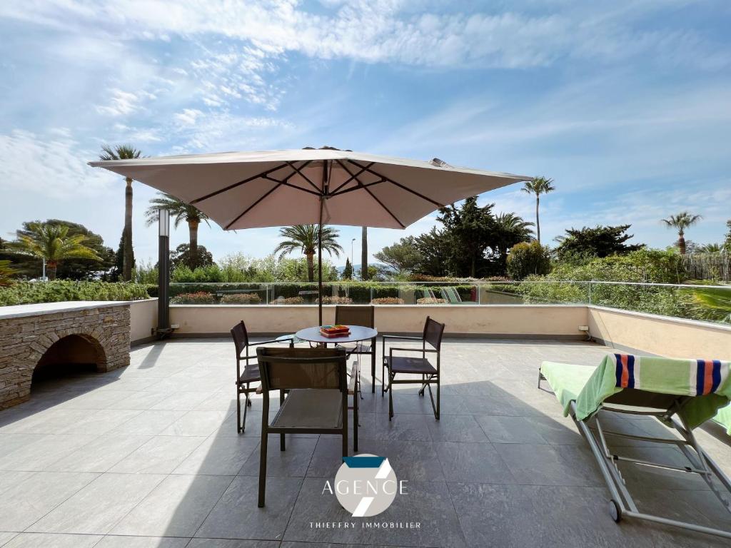 un patio avec un parasol, une table et des chaises dans l'établissement Appartement Le Beauvallon, à Grimaud