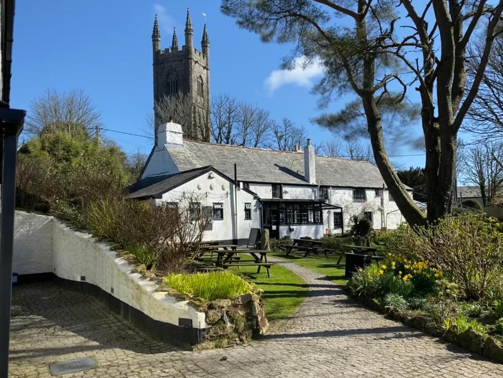 un grande edificio bianco con torre dell'orologio di The Crown Inn a Lanlivery