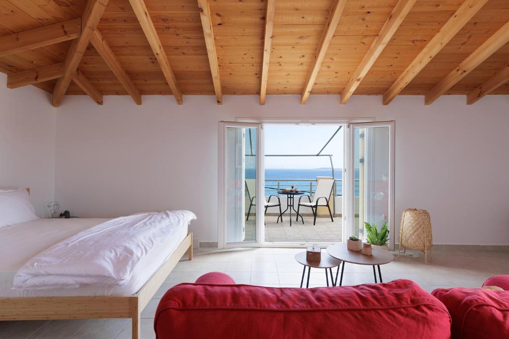 a bedroom with a bed and a couch and a balcony at The Island Life Apartments by Konnect, Ipsos Beach in Ipsos