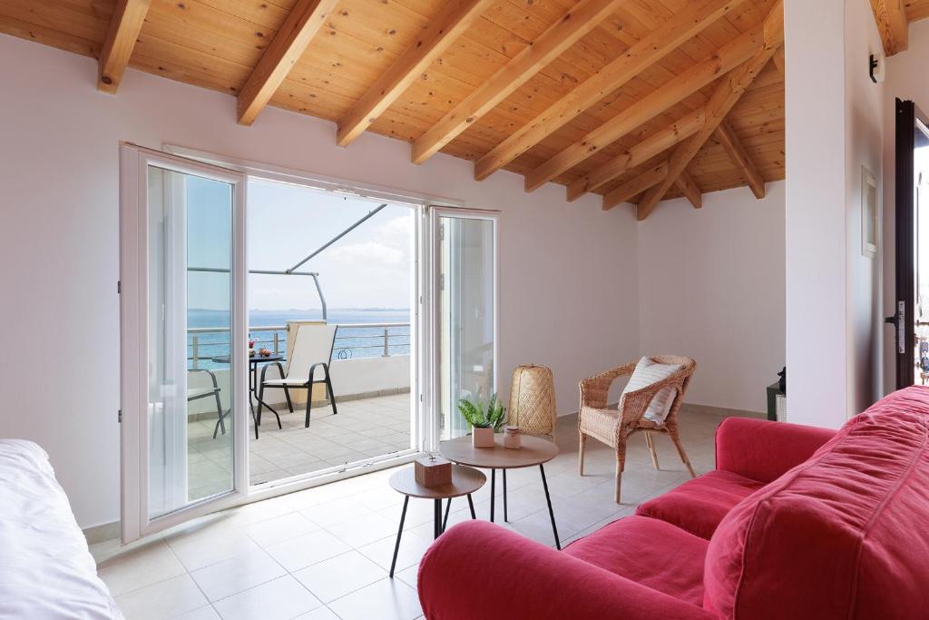 a living room with a red couch and a view of the ocean at The Island Life Apartments by Konnect, Ipsos Beach in Ýpsos