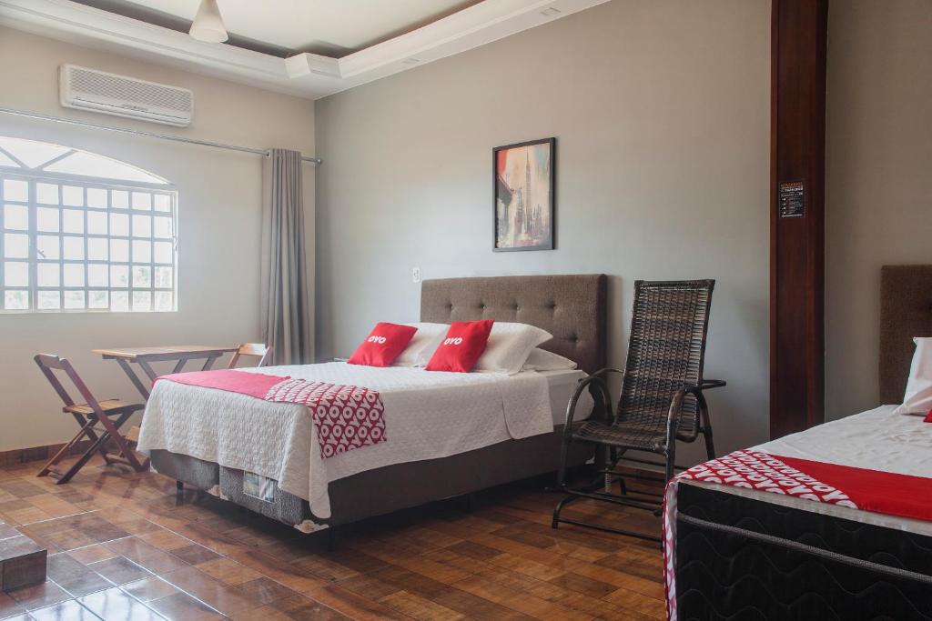 um quarto com uma cama com almofadas vermelhas e cadeiras em OYO M&J Hotel em Santo Antônio do Descoberto