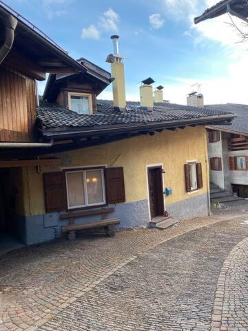 a yellow house with a bench in front of it at Casa Mia Fiemme in Carano