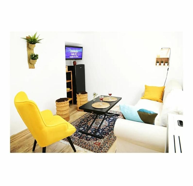 uma sala de estar com um sofá, uma mesa e uma cadeira amarela em La CaSita em Vara de Rey