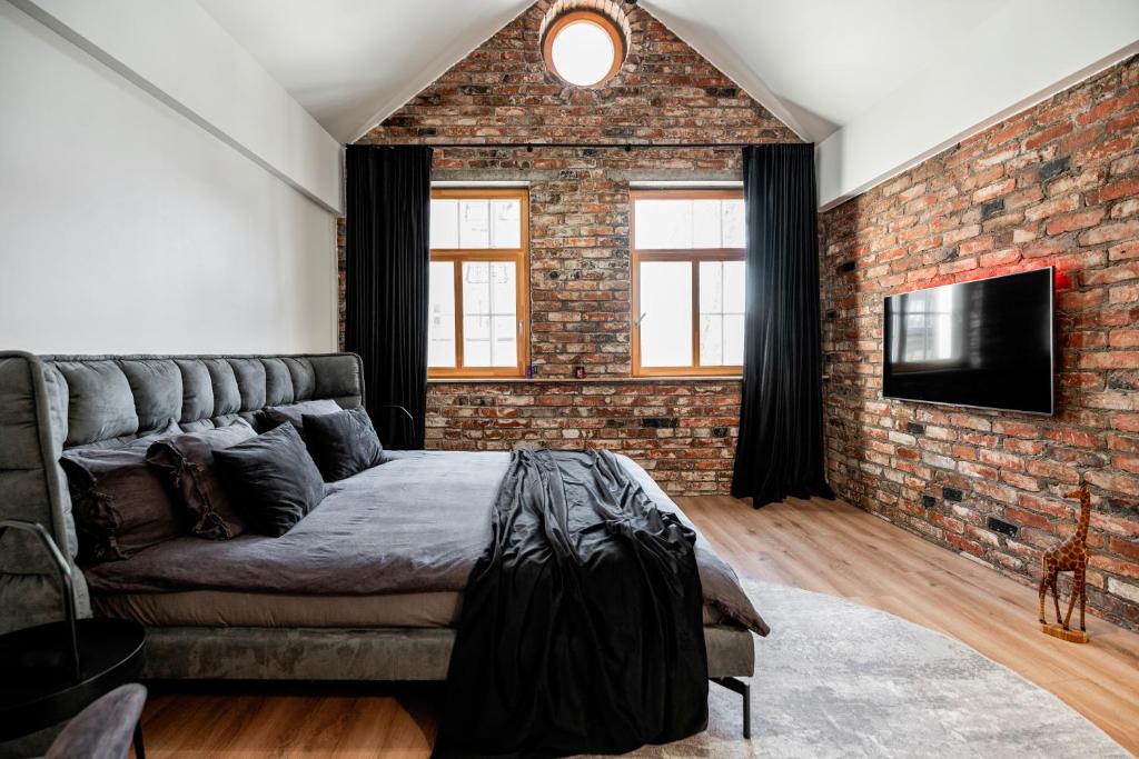 a living room with a couch and a brick wall at Apartamentai Puodžių 27 in Klaipėda