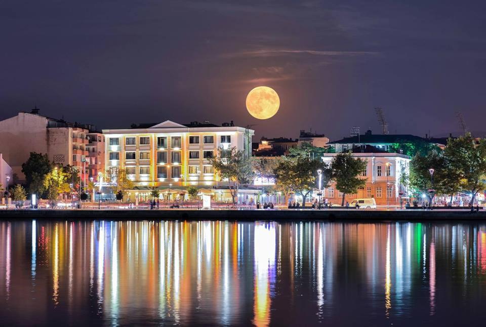 Una luna llena elevándose sobre una ciudad por la noche en Buyuk Truva Hotel, en Canakkale