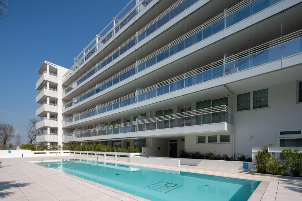 un edificio de apartamentos con piscina frente a él en Palm Beach Jesolo en Lido di Jesolo