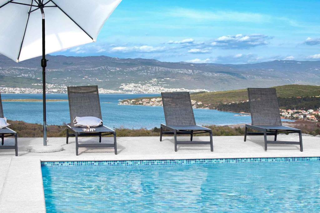 een groep stoelen en een zwembad met een parasol bij Apartments in Cizici/Insel Krk 31083 in Čižići