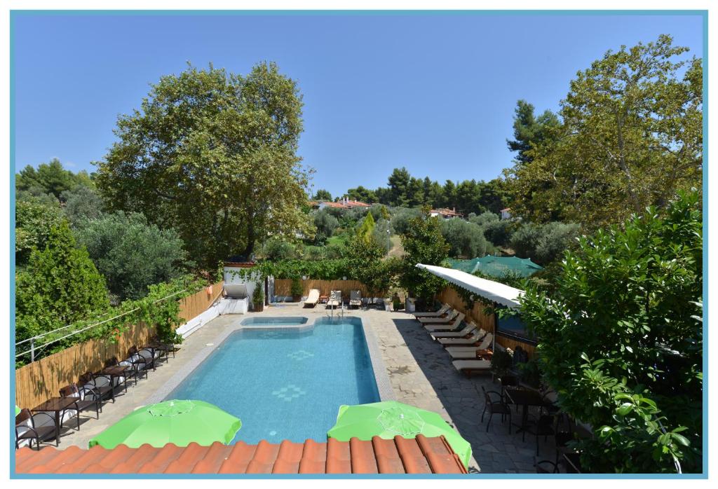 a swimming pool with chairs and umbrellas in a yard at Anna Christina Apartments in Metamorfosi