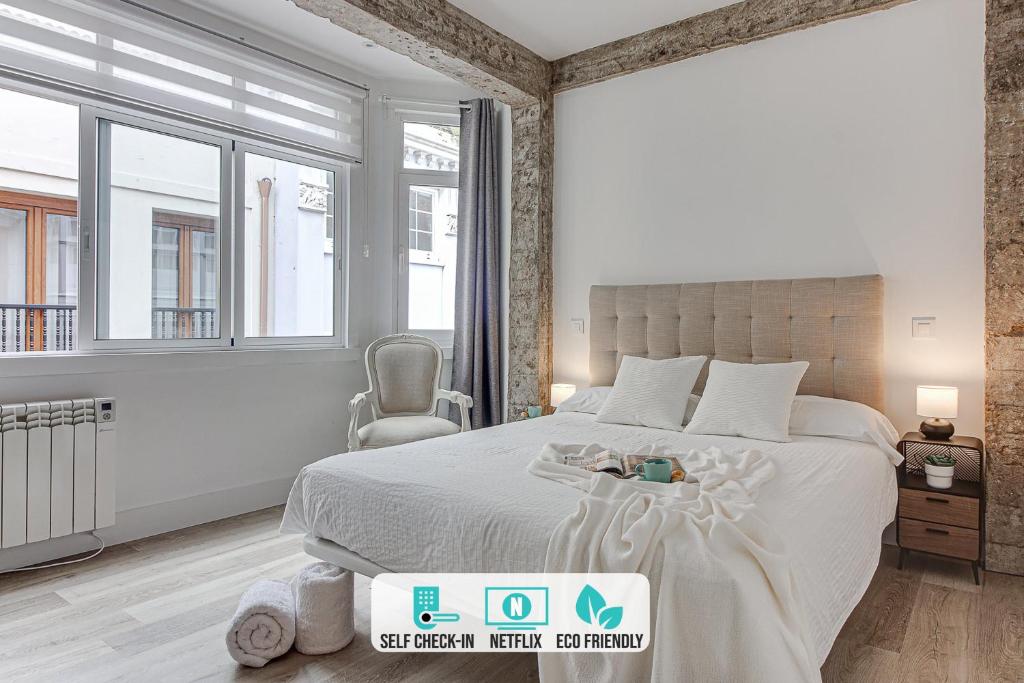 ein weißes Schlafzimmer mit einem großen Bett und Fenstern in der Unterkunft Central Square Deluxe Apartment in A Coruña