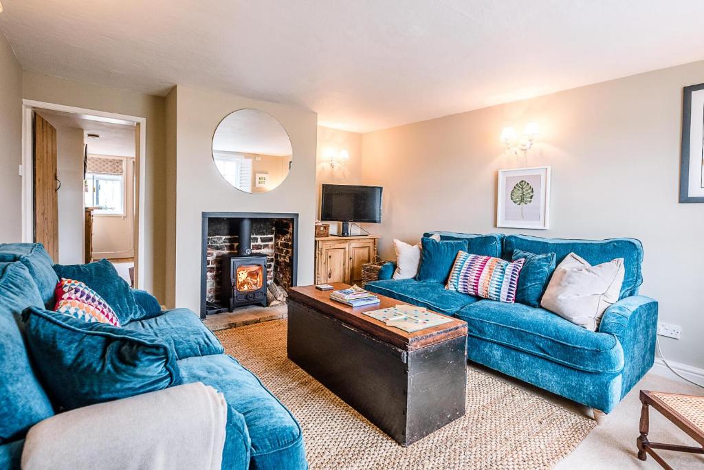 a living room with two blue couches and a fireplace at Coachman's Cottage Wrentham Air Manage Suffolk in Beccles