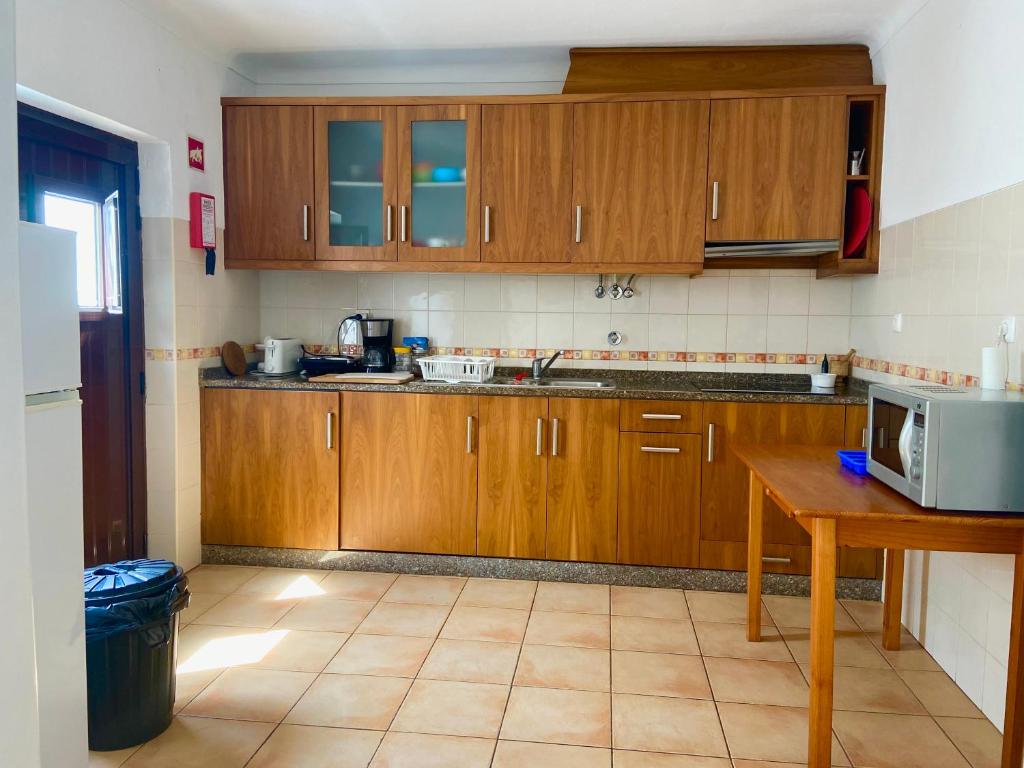 a kitchen with wooden cabinets and a tiled floor at Pirata hostel Milfontes in Vila Nova de Milfontes