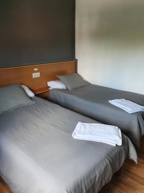 2 posti letto in una camera con asciugamani bianchi di A Concha a Lavacolla
