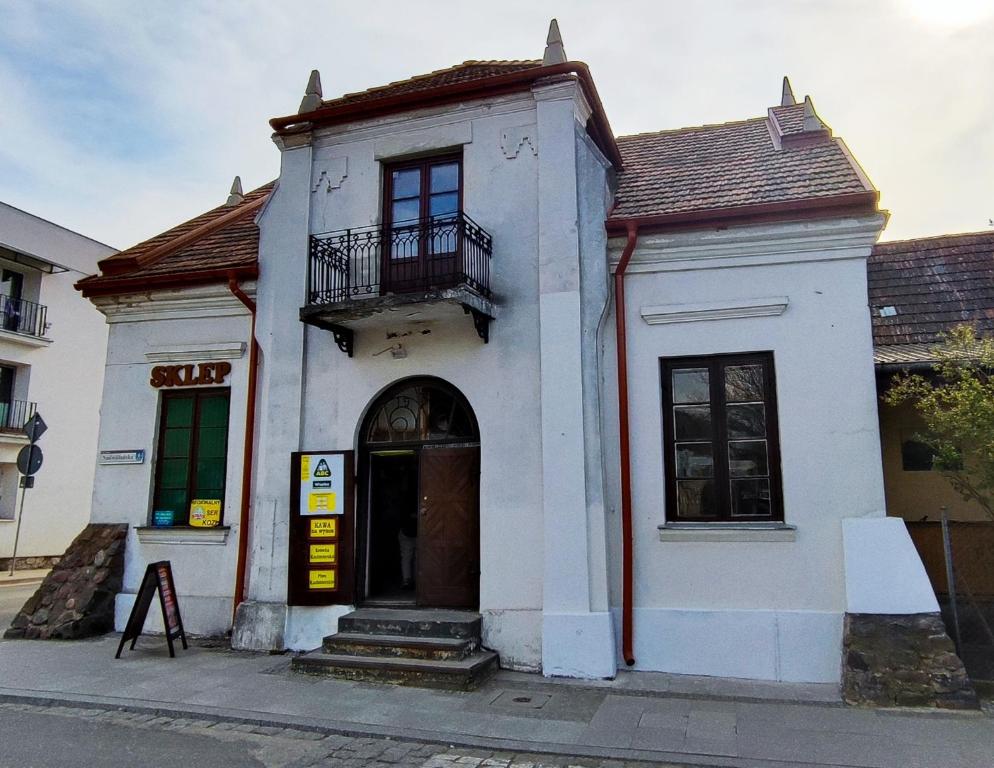 um edifício branco com uma varanda numa rua em Pokoje u Jana em Kazimierz Dolny