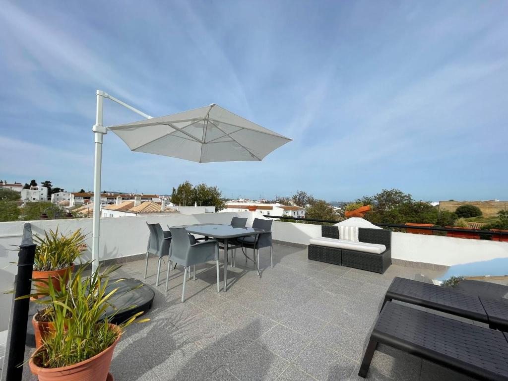 une terrasse avec une table, des chaises et un parasol dans l'établissement Casa Vista Mar, à Lagos