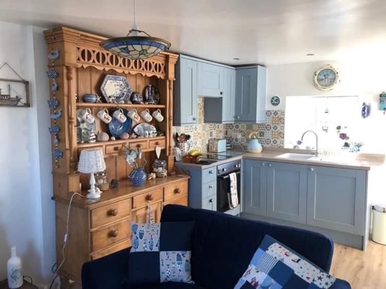 a kitchen with blue cabinets and a blue couch at The Thin Seagull 4 Beacon Terrace Ferryden in Ferryden